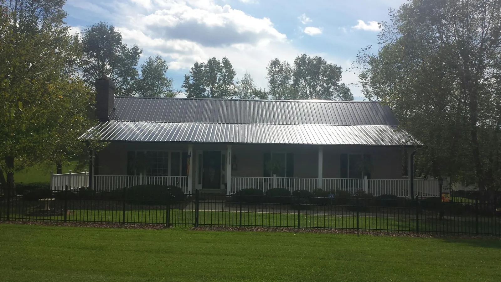 Gray metal roof on a brick ranch with a full width front porch — Gutter Guard Installation work by our crew in Iron City
