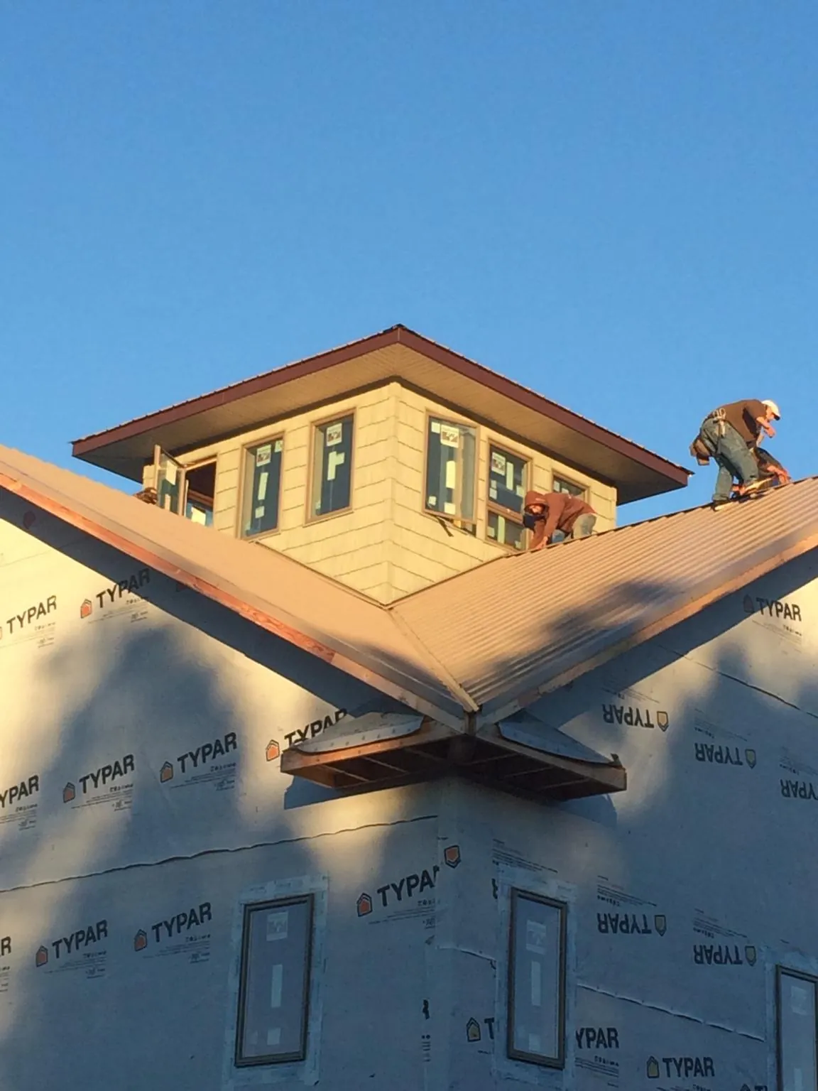 Roofers working around a rooftop cupola on a new metal roof at sunset — Roof Waterproofing in Iron City by Roofing Brothers